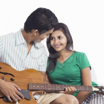 Man playing a guitar beside a woman