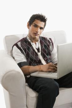 Portrait of a man sitting in an armchair and using a laptop