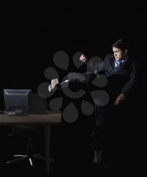 Frustrated businessman kicking a desktop pc