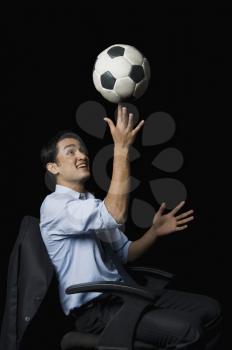 Businessman balancing a soccer ball on his finger