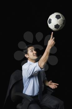 Businessman balancing a soccer ball on his finger
