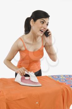 Woman ironing and talking on a mobile phone