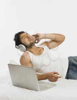 Man listening to headphones with a laptop