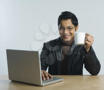 Man working on a laptop and drinking a cup of coffee