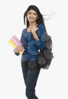 Female university student holding books and smiling