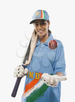 Portrait of a female cricketer tossing a cricket ball and smiling