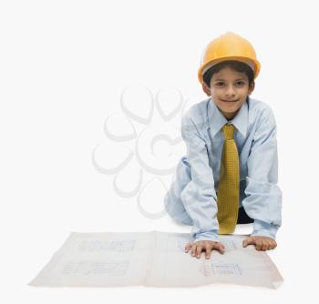 Boy dressed as an architect and working on a blueprint