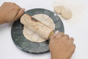 Person's hands rolling dough with a rolling pin