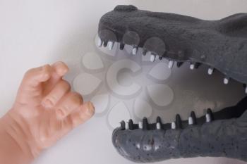 Close-up of a doll's hand in front of a toy crocodile jaw