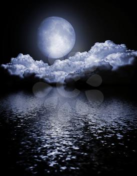 The moon in clouds in the sky over water