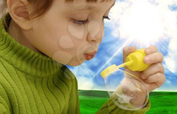 The girl inflating soap bubbles on a meadow.....