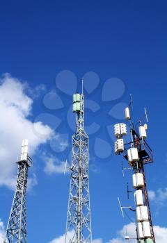 Three cellular antennas against blue sky.