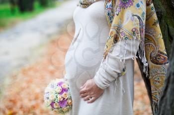 Royalty Free Photo of a Pregnant Woman Holding a Bouquet Beside a Road