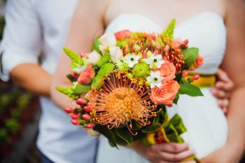 Wedding bouquet held by bride and groom. Shallow depth of field