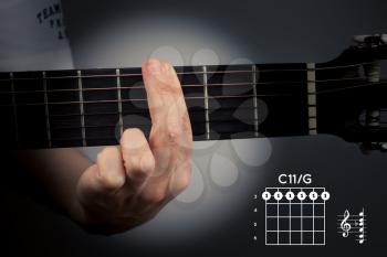 Guitar chord on a dark background with spot light. The C eleventh is a six-note chord. C11 tab fingering