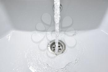 Water flows into a new white sink in the bathroom.