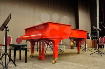 Red grand piano in the concert hall on stage.