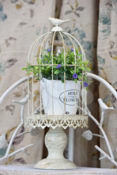 Decorative cage with flowers inside and a figure of a bird