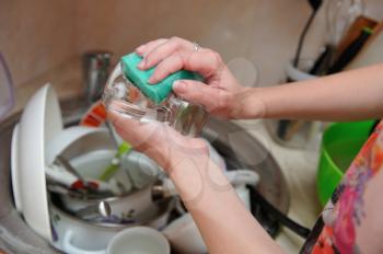 Female hands wash dishes at home in the sink