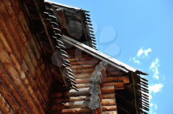 Old house and roof made of wood against the blue sky.