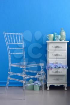 Transparent chair against a blue wall in a beautiful interior.