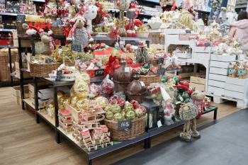 Shelf in the store with the sale of soft toys of a deer, a gray mouse, gnomes and balls for the Christmas tree for Christmas or New Year in a store with decor