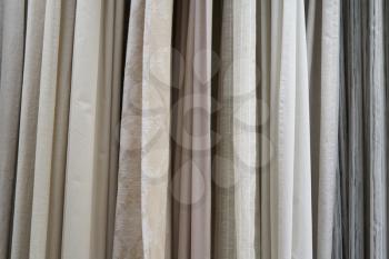 Beautiful curtains of different colors hang on the stand for sale.