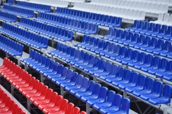 Empty stands with wet seats in red, white and blue in the stadium