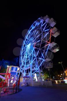 Amusement park at night with a ferris wheel and carousels.