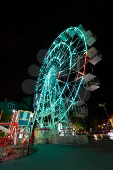 Amusement park at night with a ferris wheel and carousels.