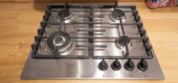 Gas stove of metallic color in the kitchen. Burners of different sizes.