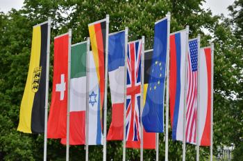 Flags of different countries in the park of the European city of Baden-Baden, Germany against the background of trees. Flags of the Commonwealth of Germany, Switzerland, France, America, England, Israel