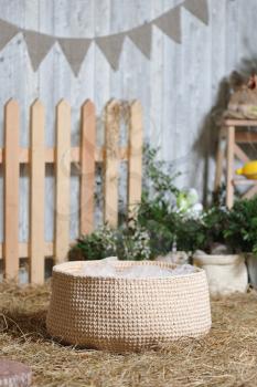 Rustic style decor, woven basket woven on dry hay against the backdrop of Easter decorations. Closeup