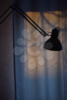 Silhouette of a table lamp on the background of a window in the morning at dawn, work until morning