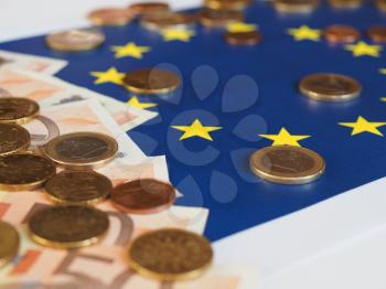 Euro banknotes and coins (EUR), currency of European Union over flag of Europe