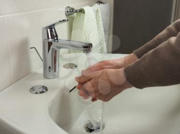 Unrecognisable man carefully washing hands at home for health safety