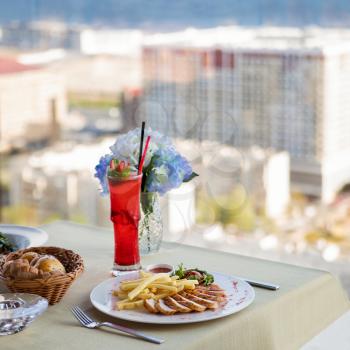 Fried chicken with french fries, red cocktail and city view
