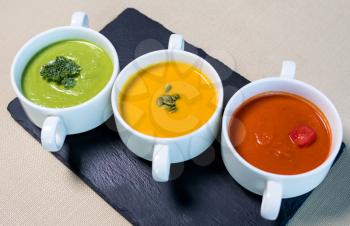 Colorful tasty soups on the black plate