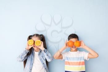 Funny little children with citrus fruit on color background�