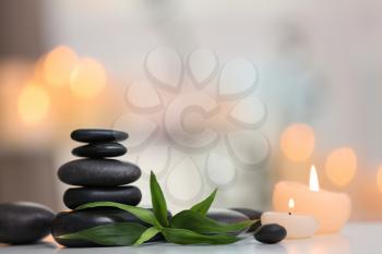 Stack of spa stones and burning candles on blurred background�