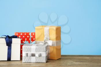 Beautiful gift boxes on table against color background�