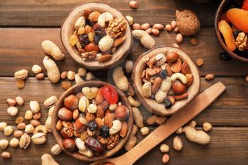 Bowls with various tasty nuts on wooden table�