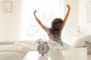 Alarm clock on table in bedroom of beautiful young woman. Morning time�