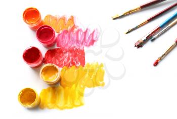 Jars with paints and brushes on white background�