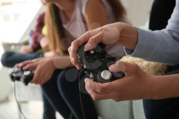Teenagers playing video games at home, closeup�