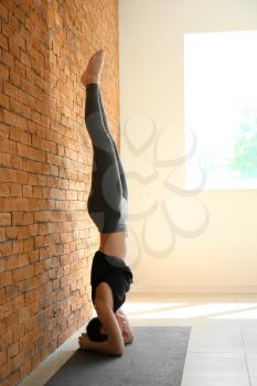 Young woman practicing yoga indoors�