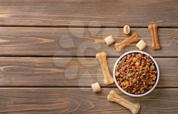 Bowl with pet food on wooden background�