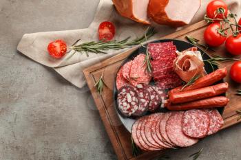 Plate with assortment of delicious deli meats on grey background�