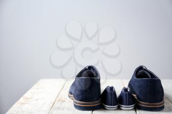 Big and small shoes on wooden table against light background. Father's day�