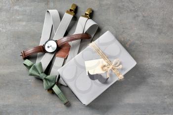 Composition with gift box and male accessories on grey textured background. Happy Father's Day celebration�